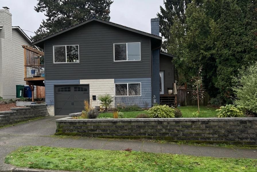 Contemporary exterior renovation with dark charcoal siding and carriage garage door